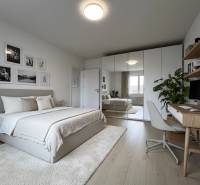 Bedroom in a 3-room apartment with wood-patterned flooring, a mirrored wardrobe, and a desk.