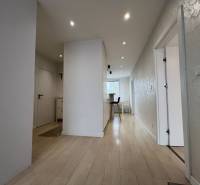 A hallway in a 3-room apartment with a wooden decor floor and white walls.