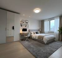A bedroom in a 3-room apartment with a wooden decor floor and a desk.