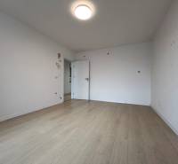 A room with a wooden decor floor in a 3-room apartment, minimalist white walls.