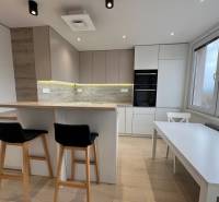 A kitchen in a 3-room apartment with light furniture and a wooden decor floor.