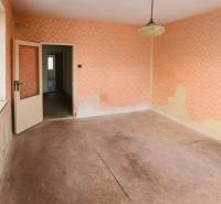 A room with wallpaper and a wood-patterned floor in a family house.