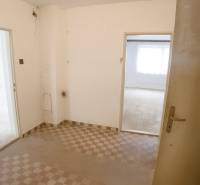 A view into the hallway of a family house with a tiled floor and white walls.