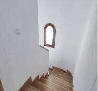 A staircase with a wooden floor decor and an arched window in a family house.