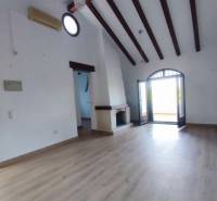 Living room in a family house with a high ceiling, fireplace, and wooden decor flooring.
