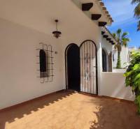 Entrance to a family house with tiles, wrought iron grilles, and a decorative lamp.