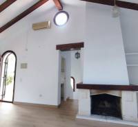 Interior of a family house with a fireplace, wooden beams, and a floor with a wooden decor.