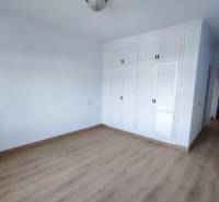 White room in a family house with a wooden decor floor and a built-in wardrobe.