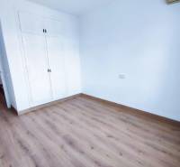 An empty room in a family house with a white wardrobe and a wooden-patterned floor.