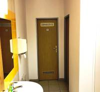 Office bathroom with a sink, mirror, and door with a symbol on the wall.