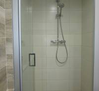 A shower enclosure with glass doors in the bathroom of a 2-room apartment.