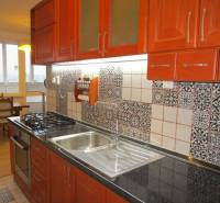 A kitchen with colorful patterns, wooden cabinets, a gas stove, and a dining table in a two-room apartment.