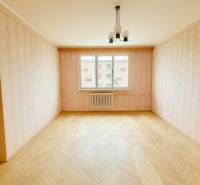A room in a 2-room apartment with a wooden decor floor and wallpaper.