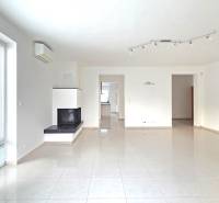 A spacious living room with a fireplace and large windows in a family house.