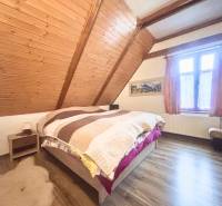 Attic bedroom of a family house with a wooden decor floor and wooden wall paneling.