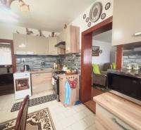 A kitchen in a family house with white tiles and furniture in a wood decor.