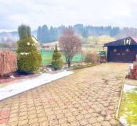 A view of the courtyard of a family house in Predmier in Turzovka with a garden house and trees.