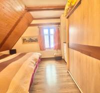 Bedroom in a family house with a wood-decor floor and a slanted wooden ceiling.