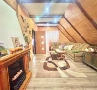 Living room in a family house with a fireplace, sofa, and wooden decor flooring.