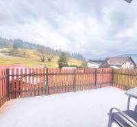 The courtyard of a family house in Predmier in Turzovka with a view of the hilly landscape and a fence.