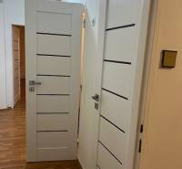 Interior of a 2-room apartment with white doors and a floor with a wooden decor.