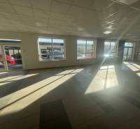 Spacious commercial spaces with large windows and tiling, illuminated by natural light.