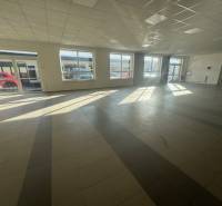 Commercial space with large windows and tiled floors bathed in sunlight.