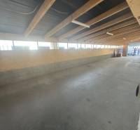 Interior of commercial spaces with wooden beams and concrete flooring.