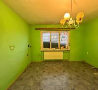 A room in a family house with green walls, a lamp, and a wooden decor floor.