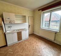 A kitchen in a family house with a wooden decor floor and a simple kitchen unit.