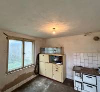 A kitchen in a family house with a ceramic stove and older furniture.