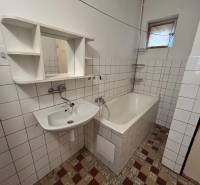 A bathroom in a family house with a bathtub, a sink, and white tiles.