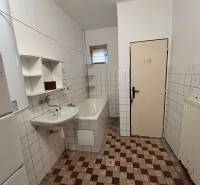 A bathroom in a family house with a bathtub and a sink, tiled with white tiles.