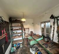 A workshop in a family house with shelves and a workbench, full of tools and materials.