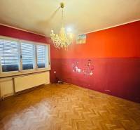 A room in a family house with a chandelier, a wooden decor floor, and colorful walls.