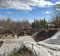 A construction site in Starý Smokovec for the development of a recreational apartment surrounded by trees and building materials.