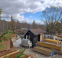 Construction site in Starý Smokovec, with piles of wood, a steel structure, and a small cabin.