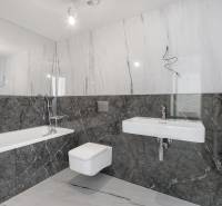 A bathroom with marble tiles, a bathtub, a sink, and a wall-mounted toilet in a 3-room apartment.