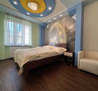A bedroom in a two-room apartment with a wooden decor floor and an artistic wall.