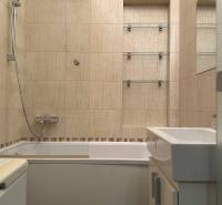 Bathroom with a bathtub and shower in a 2-room apartment with ceramic tiles.