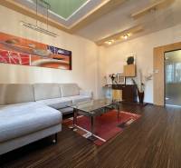 Living room in a two-room apartment with a sofa, glass table, and wooden decor flooring.