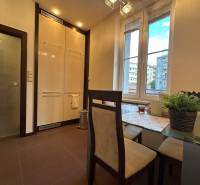 Dining area in a 2-room apartment with a large window and a table with square chairs.