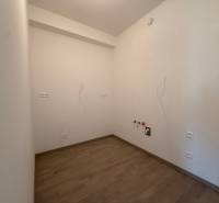 An empty room in a 2-room apartment with wood-patterned flooring and connections.