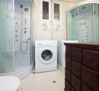 Bathroom in a 2-room apartment with a washing machine, shower, and cabinet.