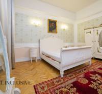 Bedroom in a 2-room apartment with wood-patterned flooring and floral wallpaper.
