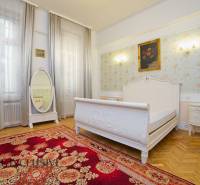 A bedroom in a 2-room apartment with delicate wallpaper, a mirror, and a wooden decor floor.