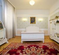 Bedroom with wood-patterned flooring, large mirror, and red ornamental carpet.
