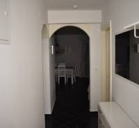 A hallway in a family house with a mirror, white furniture, and an entrance to the dining room.