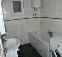 A bathroom in a family house with a bathtub, a washing machine, and a gas boiler on the wall.