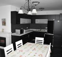 A kitchen with black furniture, a dining table, and a white fireplace in a family house.
